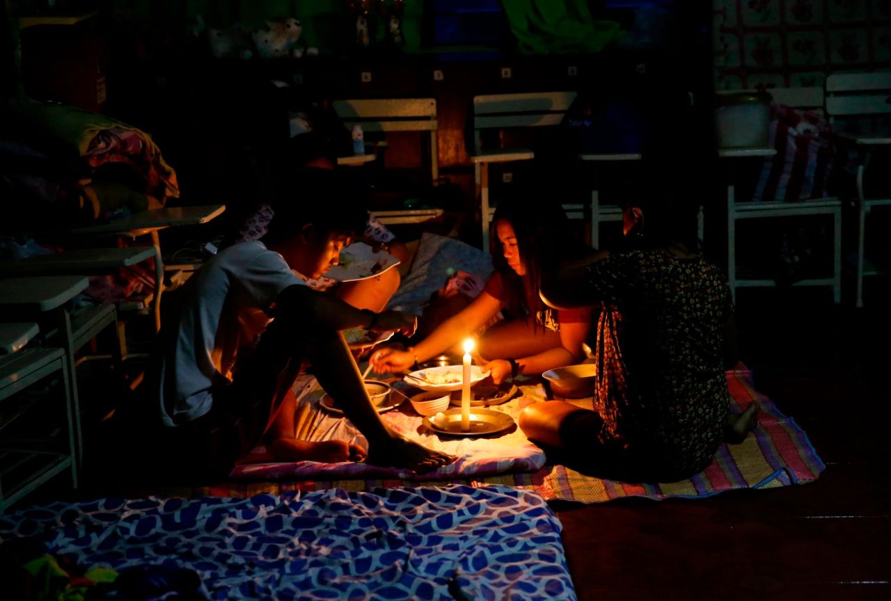 A family shares a meal by flashlight inside a temporary evacuation center after electricity was shut off following the onslaught of Typhoon Mangkhut in the city of Tuguegarao, Philippines, on Saturday.