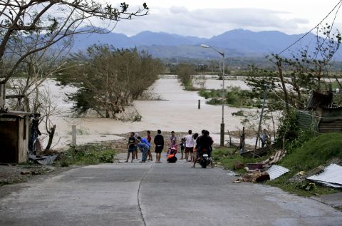 Residents stand by a flooded road in Tuguegarao city in northeastern Philippines, on Saturday, September 15.
