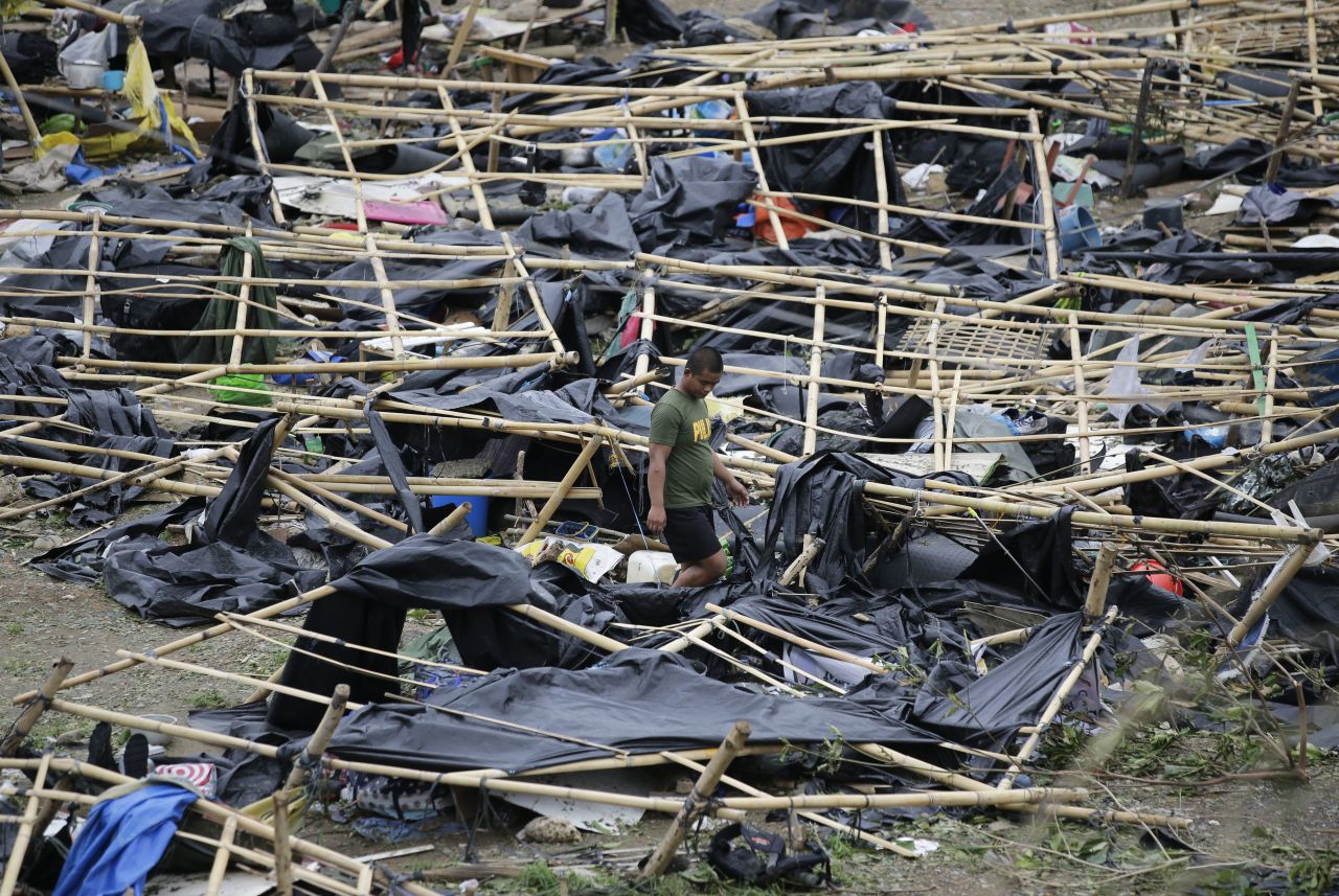 A policeman walks through makeshift tent shelters damaged by strong winds in Tuguegarao.