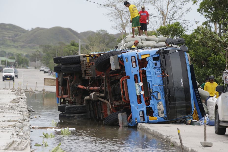 Workers transfer sacks of grains from a toppled truck in northeastern Philippines on Sunday, September 16.