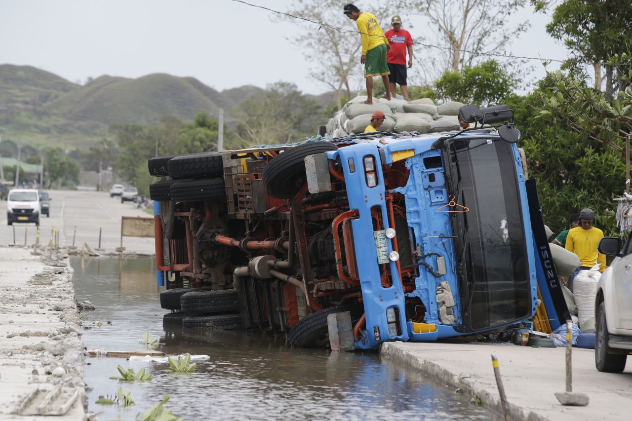 Workers transfer sacks of grains from a toppled truck in northeastern Philippines on Sunday, September 16.