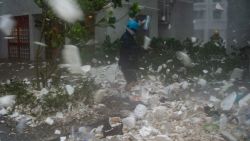 A photojournalist walks amongst plastic debris blown by strong winds in the residential district of Heng Fa Chuen during Super Typhoon Mangkhut in Hong Kong on September 16, 2018. (Photo by Philip FONG / AFP)        (Photo credit should read PHILIP FONG/AFP/Getty Images)