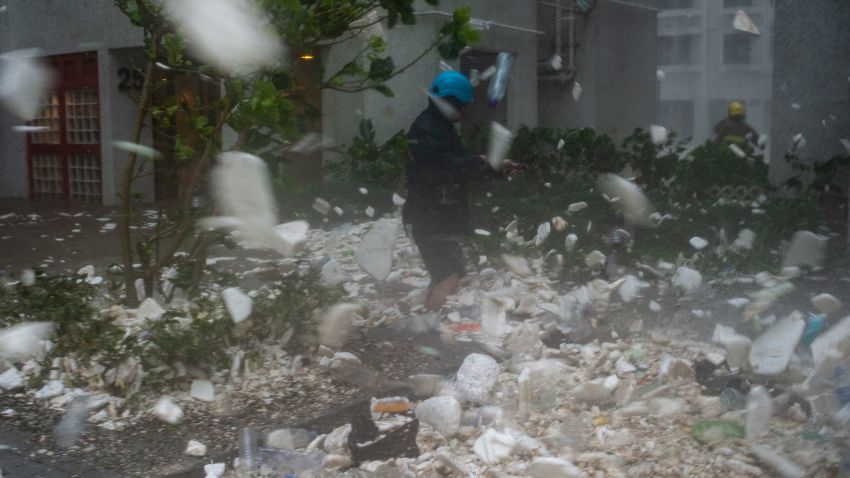 A photojournalist walks amongst plastic debris blown by strong winds in the residential district of Heng Fa Chuen during Super Typhoon Mangkhut in Hong Kong on September 16, 2018. (Photo by Philip FONG / AFP) (Photo credit should read PHILIP FONG/AFP/Getty Images)