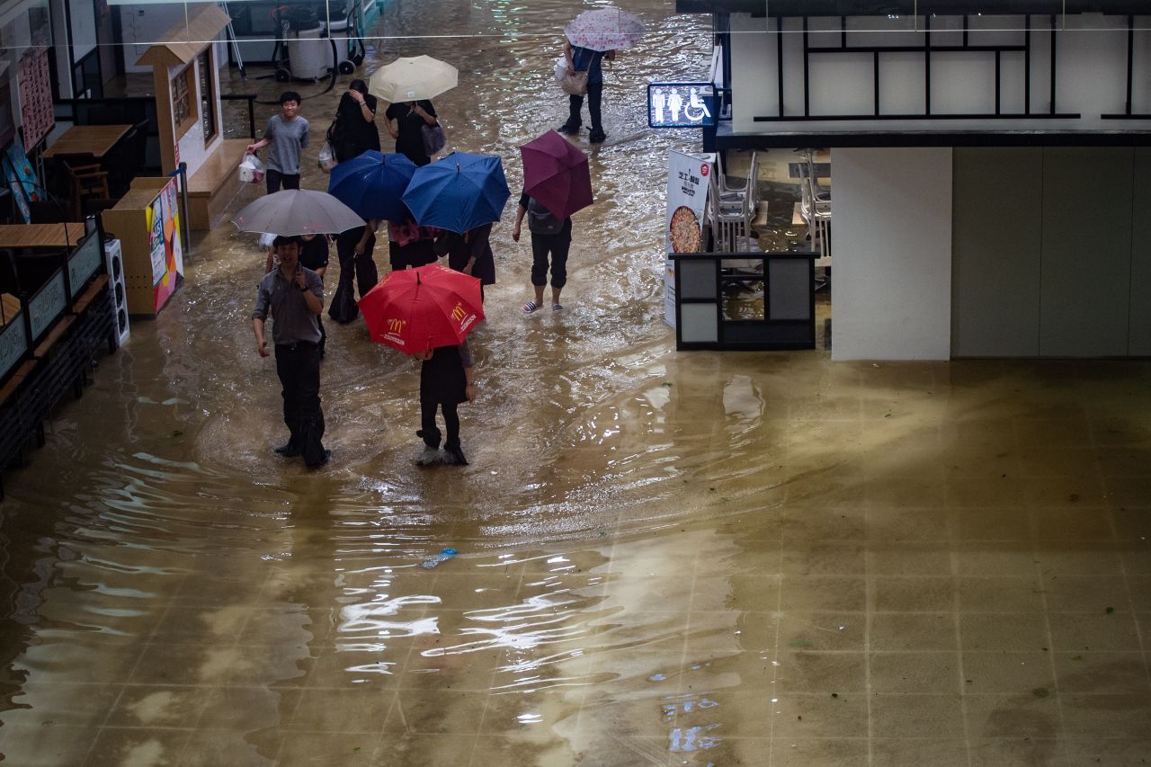 People walk through a flooded shopping mall in Heng Fa Chuen district on Sunday, September 16.