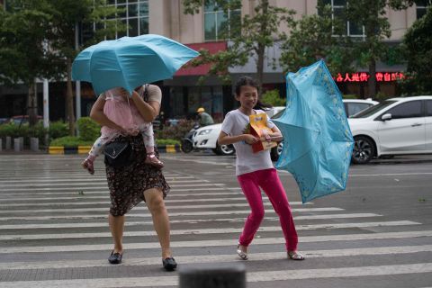 People battle strong winds as they cross a street in China's Guangdong province on Sunday, September 16.