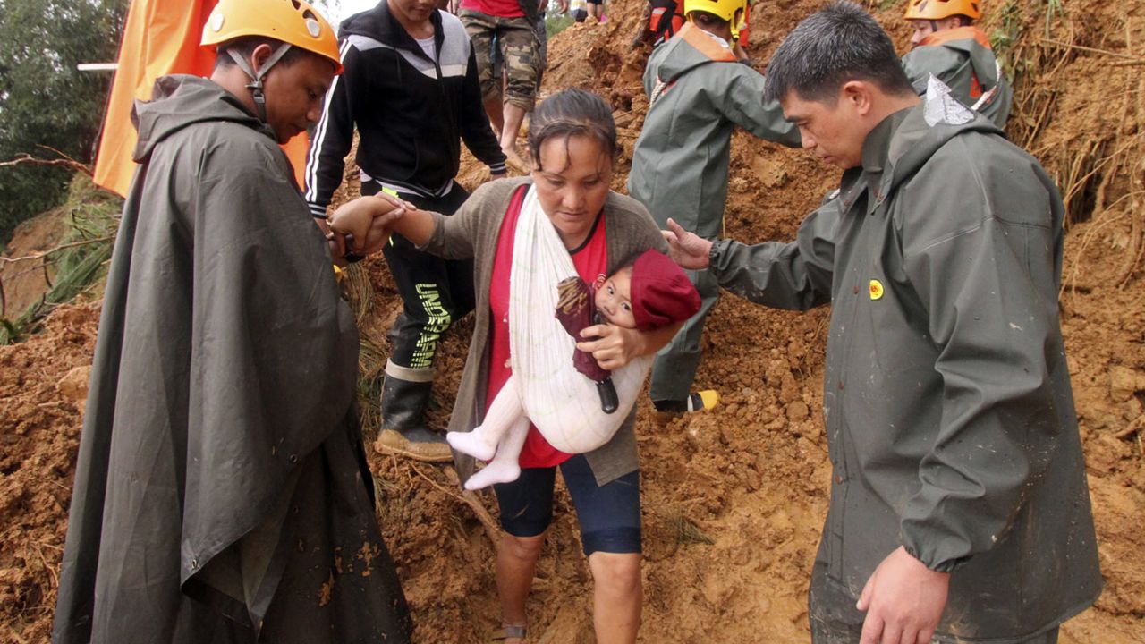 Rescuers assist a mother and her child as they move to safer grounds following landslides in the Benguet province in northern Philippines on Sunday. 