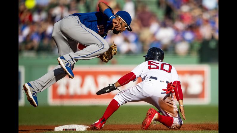Mookie Betts of the Boston Red Sox slides into second base as Amed Rosario of the New York Mets jumps to attempt to catch an overthrown ball during the first inning of the game at Fenway Park on Saturday, September 15.
