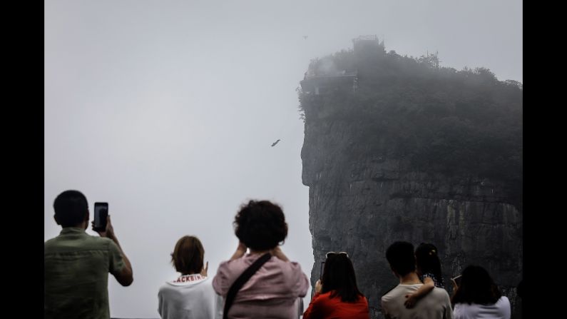 Tourists watch a wingsuit flyer jump off a mountain during the 7th World Wingsuit Championship at Tianmen Mountain on Saturday, September 15.