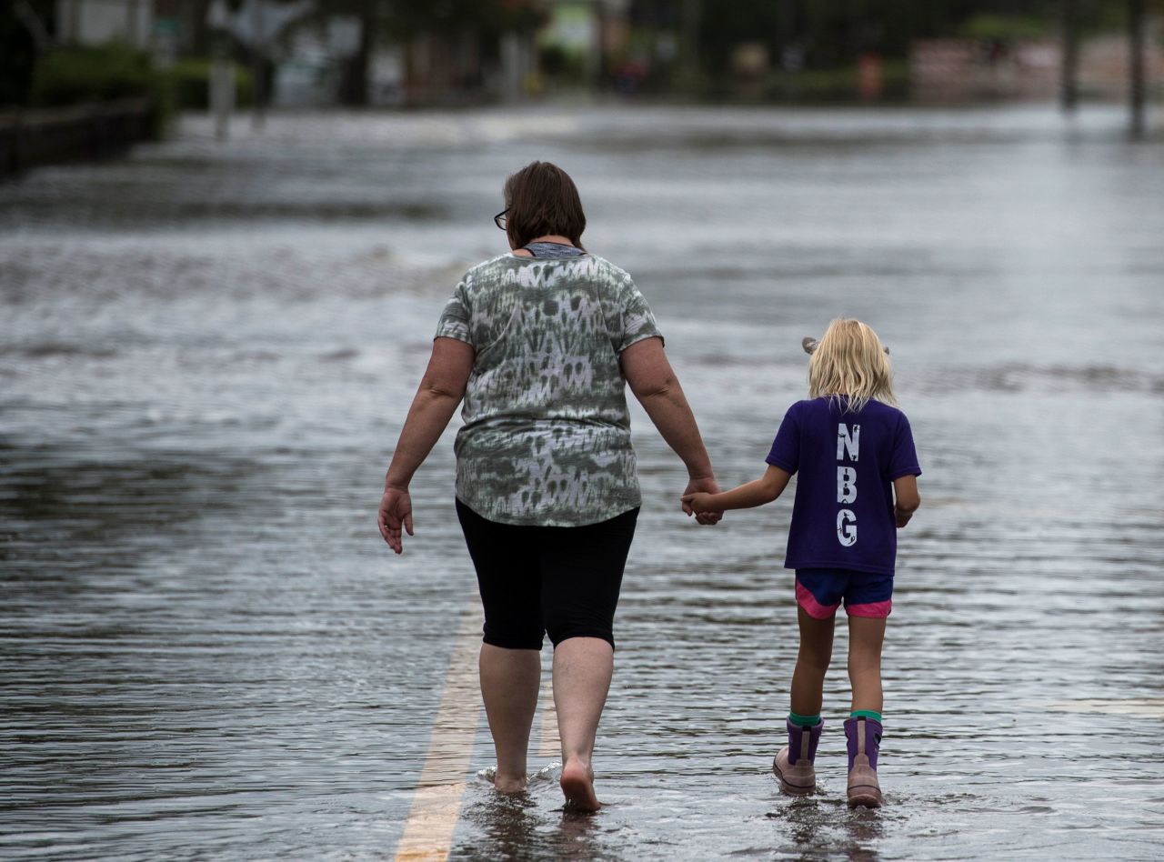 A woman and a young girl walk down a flooded road in Pollocksville on September 16.