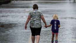 A woman holds a young girl's hand as they walk down a road flooded by Hurricane Florence in Pollocksville, North Carolina, on September 16, 2018. - Catastrophic floods raised the threat of dam breaks and landslides across the southeastern United States, prolonging the agony caused by a killer hurricane that has left more than a dozen people dead and billions of dollars in damage. (Photo by Andrew CABALLERO-REYNOLDS / AFP)        (Photo credit should read ANDREW CABALLERO-REYNOLDS/AFP/Getty Images)