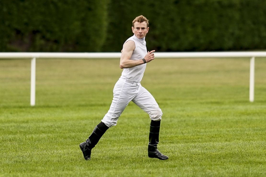 Jockey Ryan Moore races across the track after arriving from Doncaster Racecourse by helicopter.