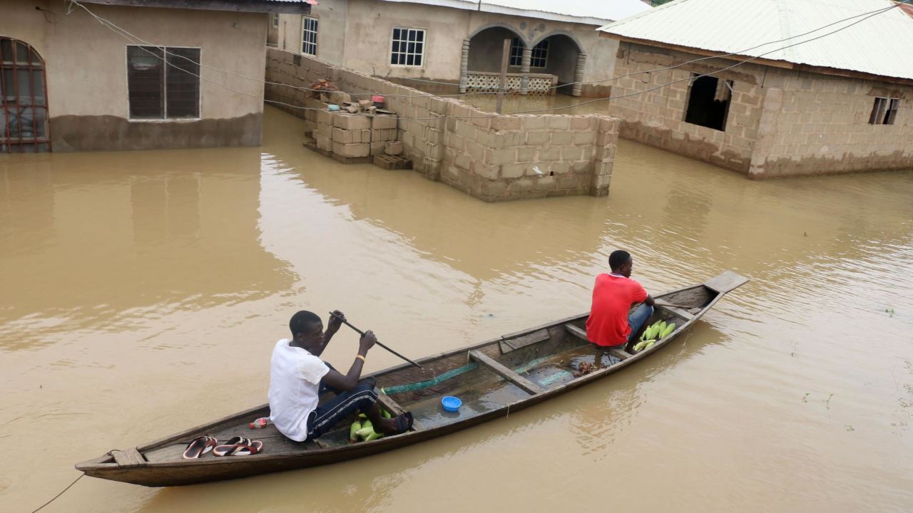 Residents steer a dugout canoe past flooded houses in Lokoja capital of Kogi State on September 14, 2018. 