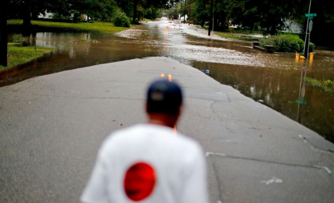 Helen McKoy walks down a flooded street in her neighborhood in Fayetteville on Sunday.