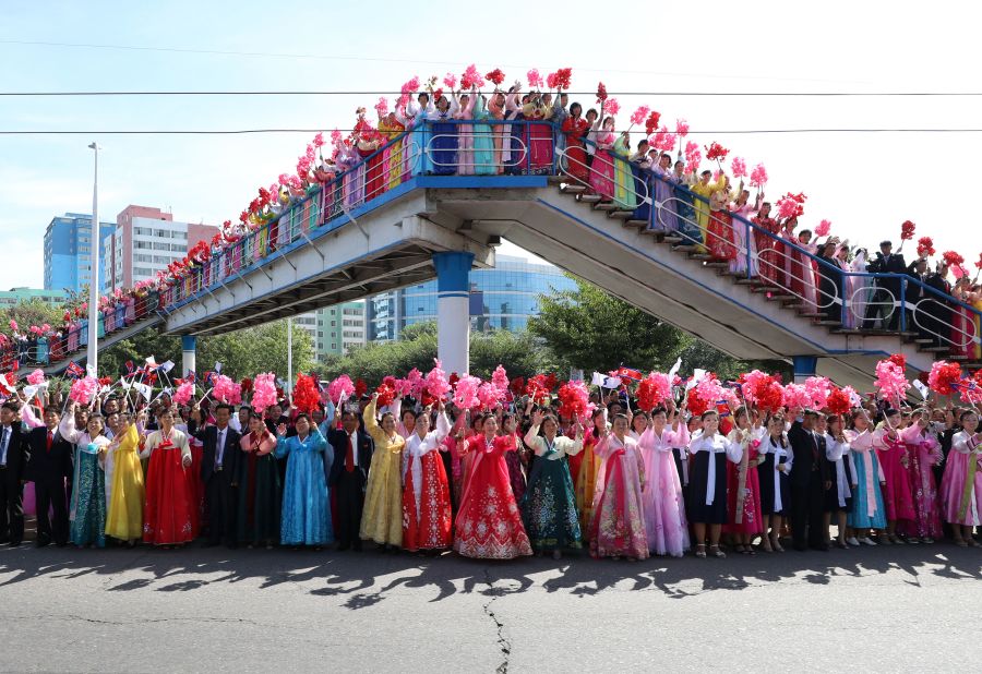 North Koreans wave bouquets and flags as they watch the two leaders' parade in Pyongyang on September 18.