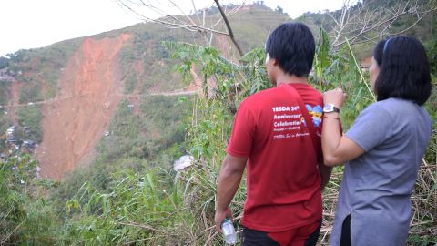People look at the landslide site in Itogon as rescuers used shovels and their bare hands to claw through mounds of rocky soil.