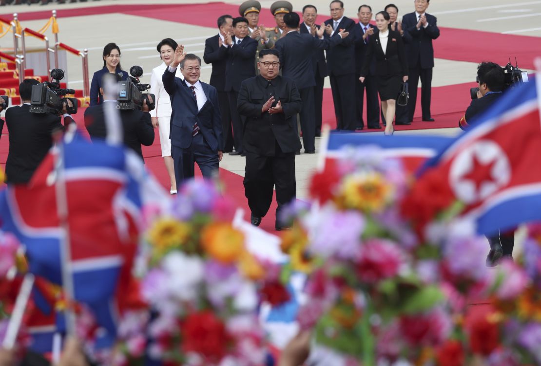 South Korean President Moon Jae-in, center left, waves as North Korean leader Kim Jong Un, center right, applauds upon Moon's arrival at Sunan International Airport in Pyongyang Tuesday.