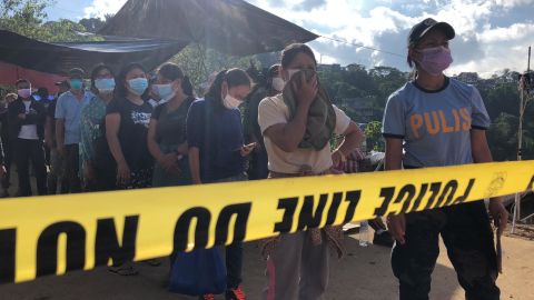 Family members wait to view recovered bodies from the landslide, hoping to identify their loved ones.