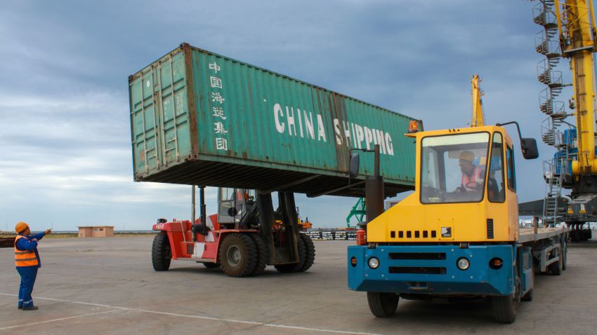 Workers load a shipping crate in the Kazakhstan's Caspian seaport of Aktau, on August 14, 2018. - With the outlines of its six idle cranes obscured by thick fog and pouring rain, Kazakhstan's Caspian seaport Aktau seems an unlikely frontier on China's much-hyped new silk road. But the sleepy port, which has been badly hit in recent years by new oil routes, is vying for a slice of the pie as competition for Chinese trade warms up on the shores of the world's largest inland sea. (Photo by Talant KUSAIN / AFP)        (Photo credit should read TALANT KUSAIN/AFP/Getty Images)