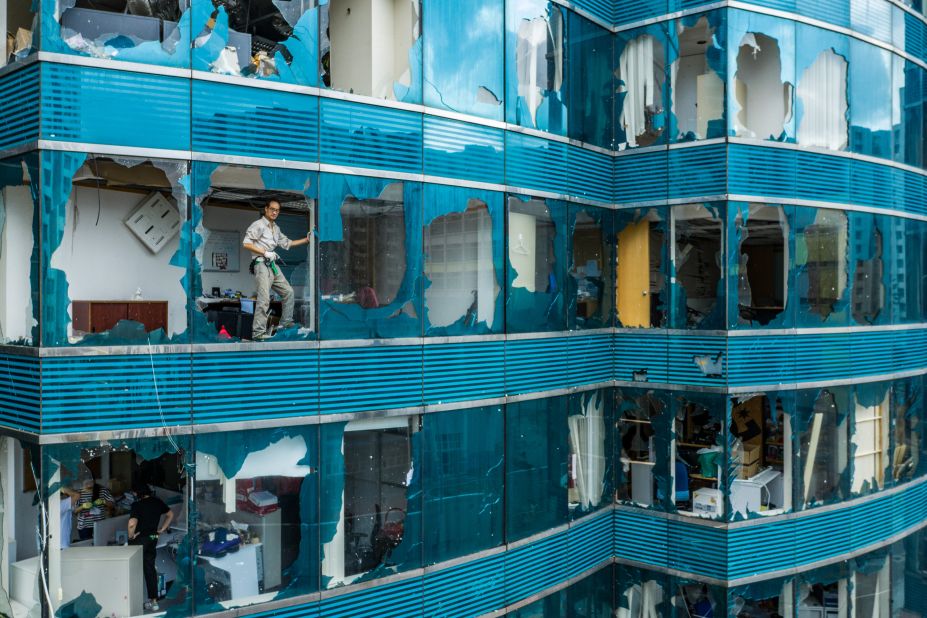 A man looks out of a damaged building in Hong Kong after Typhoon Manghkut.