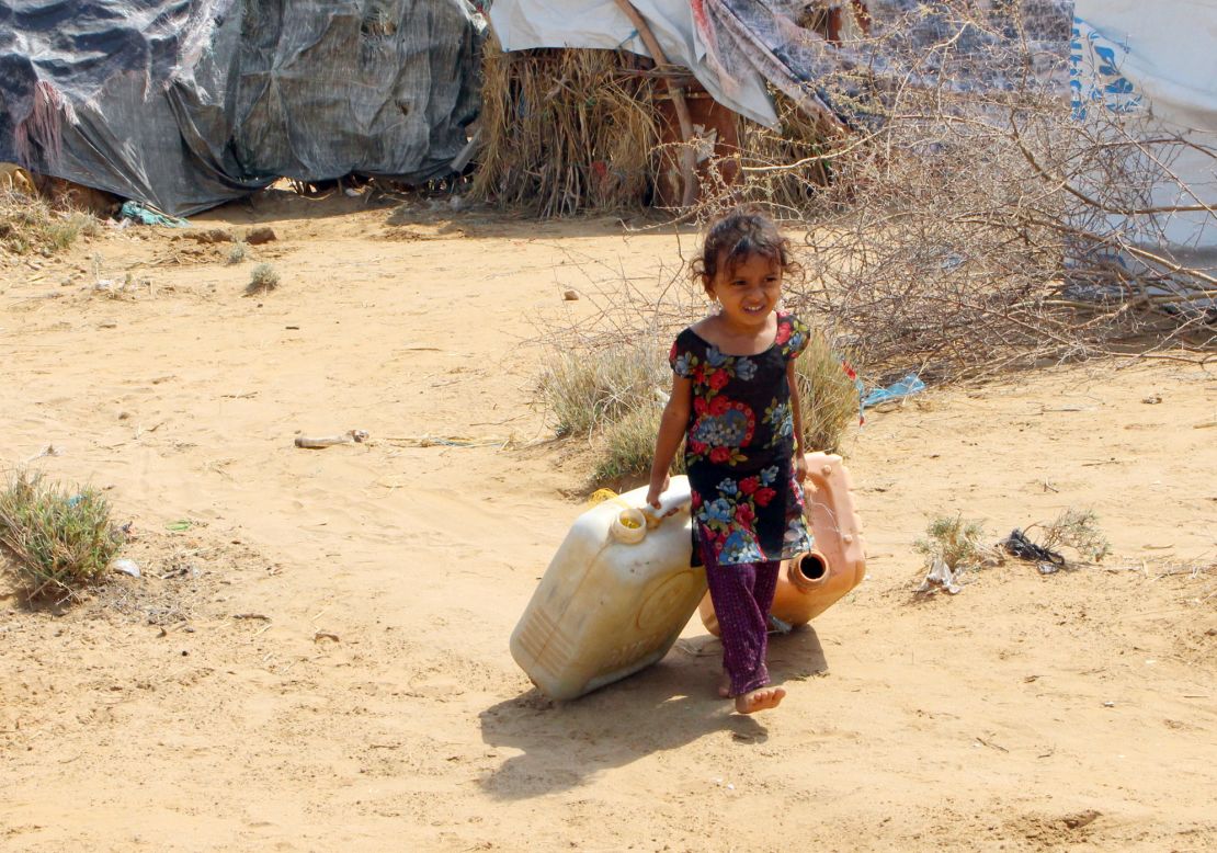 A displaced Yemeni girl from Hodeidah carries water containers at a makeshift camp in a village in the northern district of Abs.