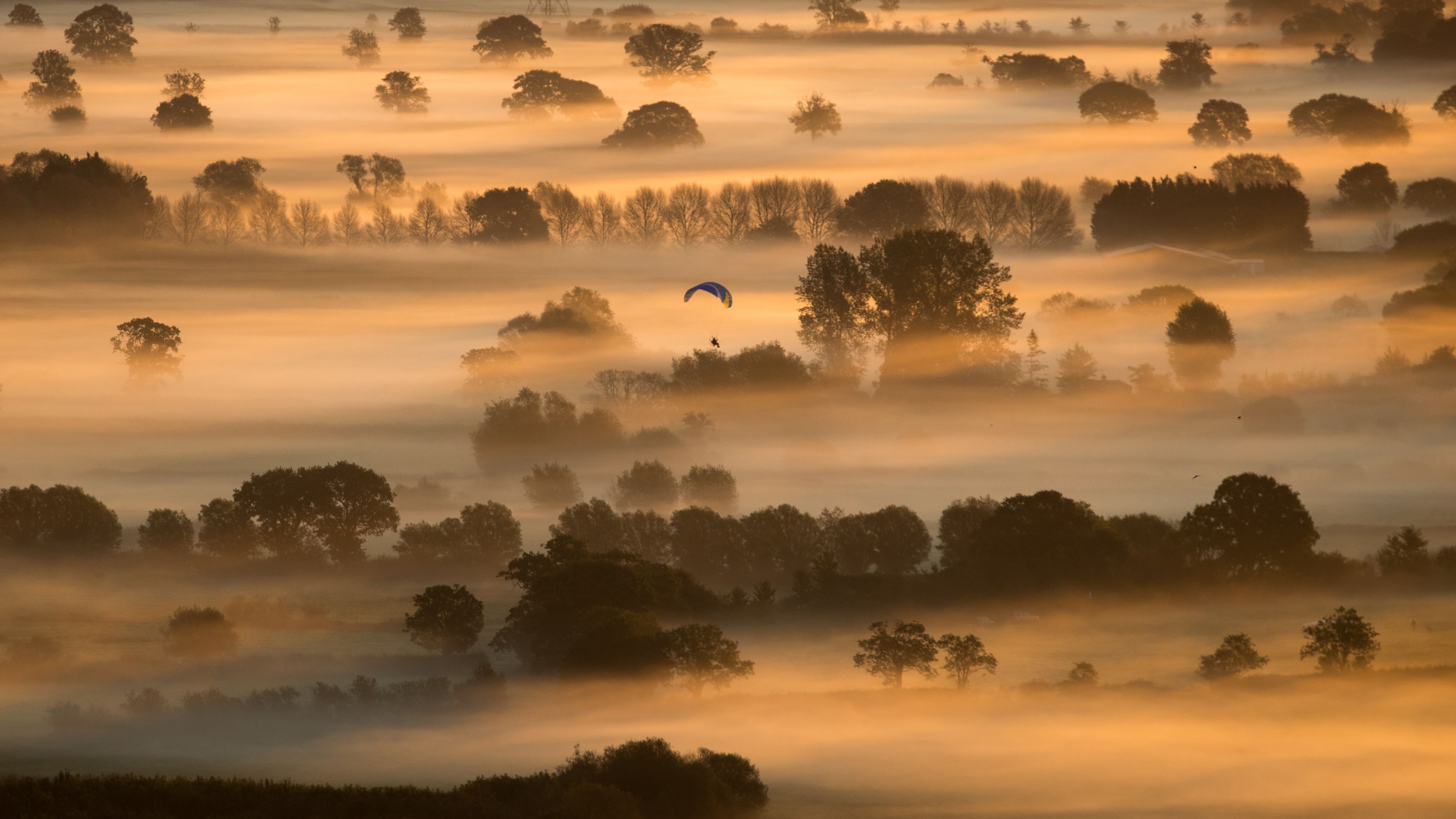<strong>Glastonbury, England:</strong> A lone paraglider enjoys the early morning mist that lingers in fields as the autumn sun rises near Glastonbury, southwest of Bath. 