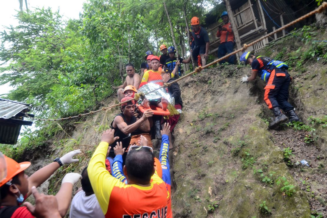 Rescuers carry a resident brought out from the landslide site.