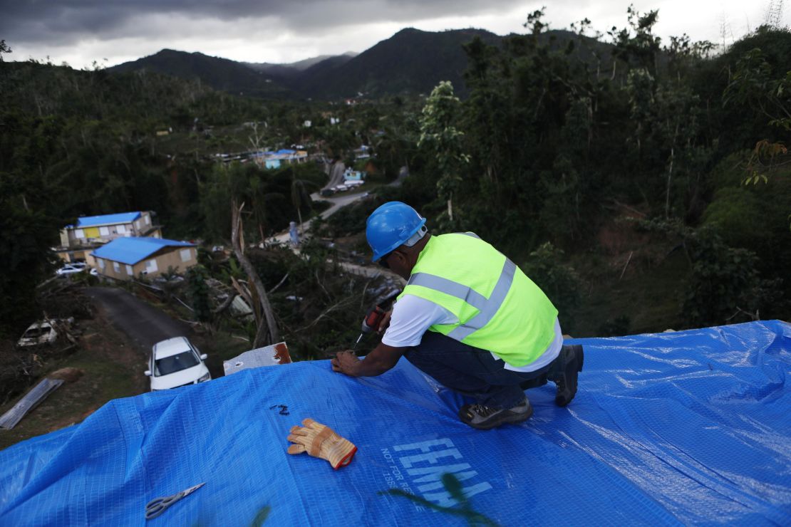 A contractor helps apply a FEMA tarp to a home in Morovis on December 20. 