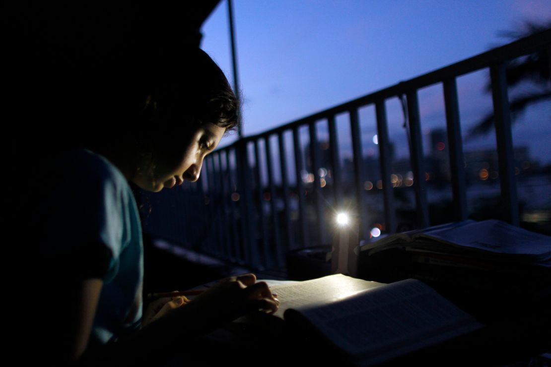Alana Rivera, age 10, does her daily homework in her apartment balcony lit by a cell phone light in San Juan, last November.