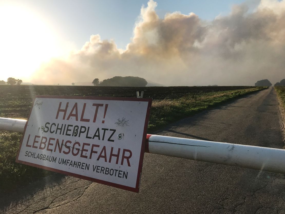 A sign reads, "Stop! Artillery range, danger to life" as smoke from the moor fire rises into the sky.