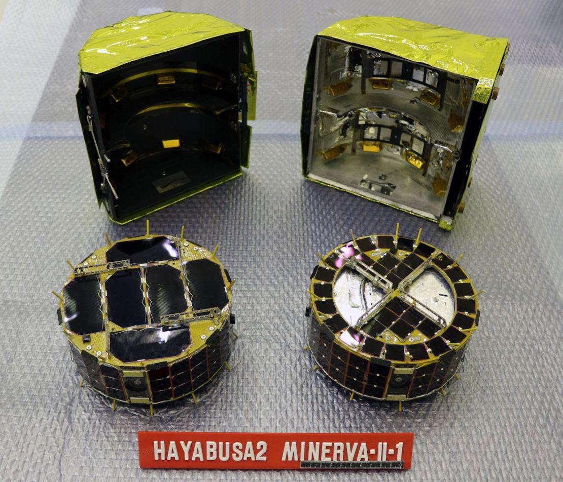 The small rovers, MINERVA-II1. Rover-1A is on the left and Rover-1B is on the right. Behind the rovers is the cover in which they are stored.