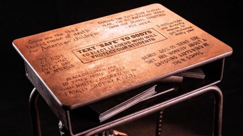The top of the desk shows staggering statistics about gun violence in America.