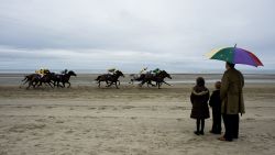 LAYTOWN, IRELAND - SEPTEMBER 08: Racegoers shelter from the rain as the runners pass during the Laytown race meeting run on the beach on September 08, 2011 in Laytown, Ireland. (Photo by Alan Crowhurst/Getty Images)