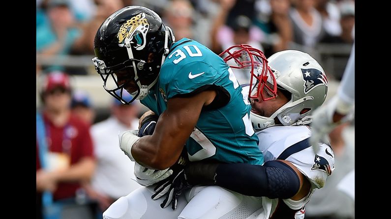New England Patriots linebacker Kyle Van Noy's face mask comes undone as he tackles Jacksonville Jaguars running back Corey Grant on Sunday, September 16, in Jacksonville, Florida.