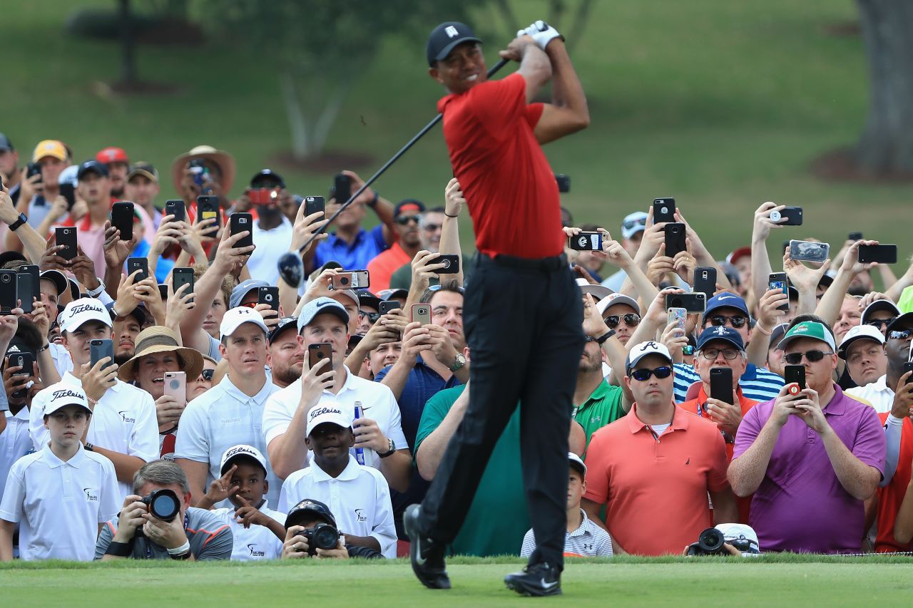Fans take pictures as Woods tees off on the fourth hole Sunday. Thousands of fans followed Woods during the final round.