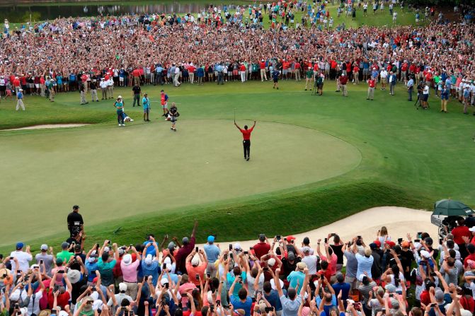 Woods raises his hands in the air after tapping in a par putt on his final stroke. It was Woods' 80th victory and his first since 2013.