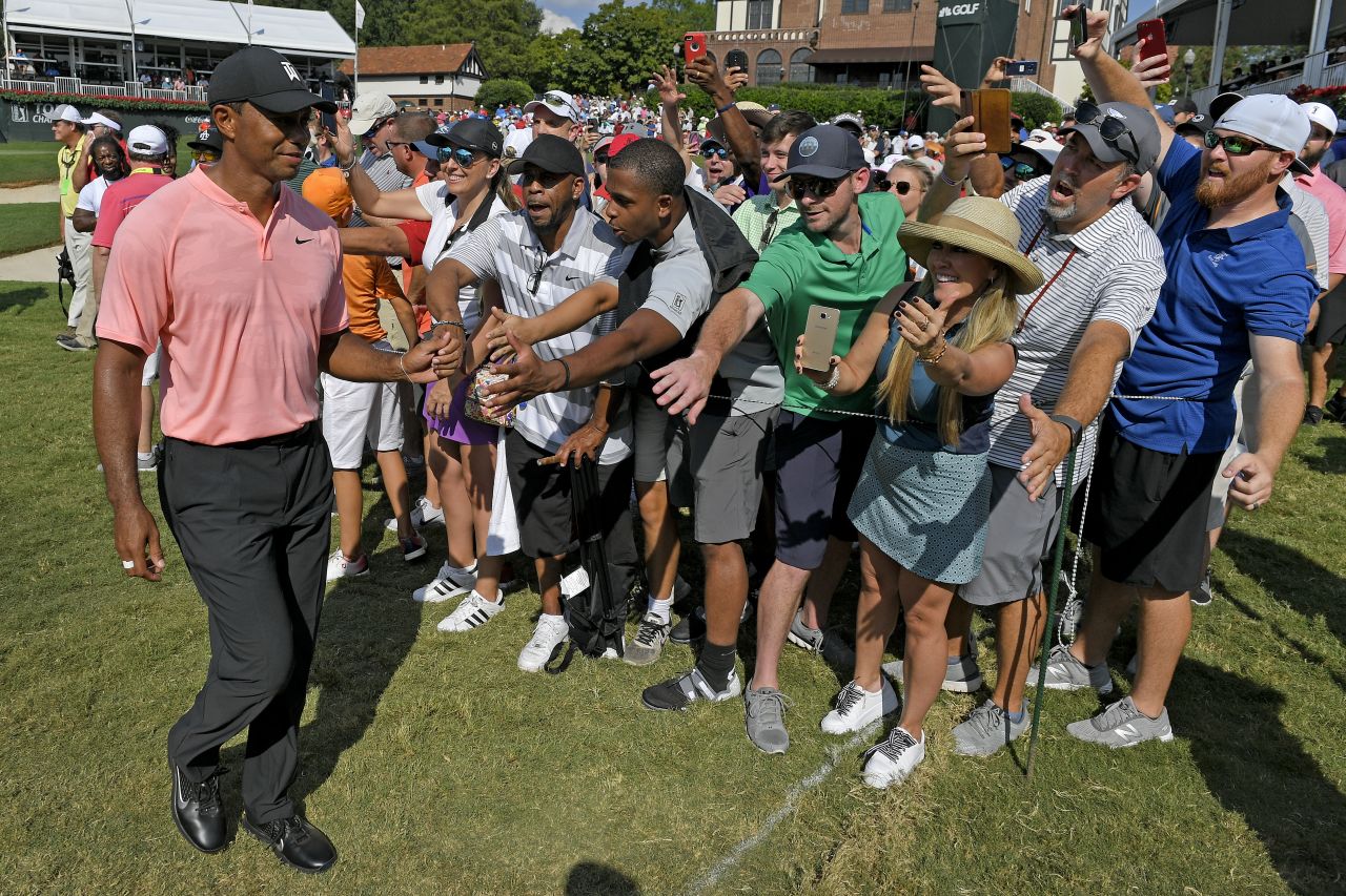 Tiger Woods fist-bumps with fans after leaving the 18th hole during the first round on Thursday, September 20.