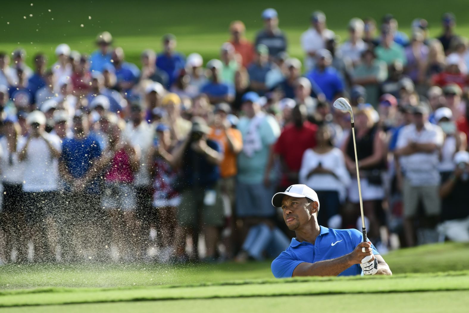 Woods shoots out of the sand onto the 15th green Saturday during the third round.