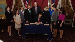 Rachael Denhollander, second from right, and other survivors of Larry Nassar's abuse watch Michigan Lt. Gov. Brian Calley sign a law that allows more time for victims of child sexual abuse to seek criminal charges. 