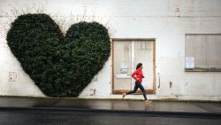A female runs in front of a heart shaped vine on an building in Bellingham, Washington.
