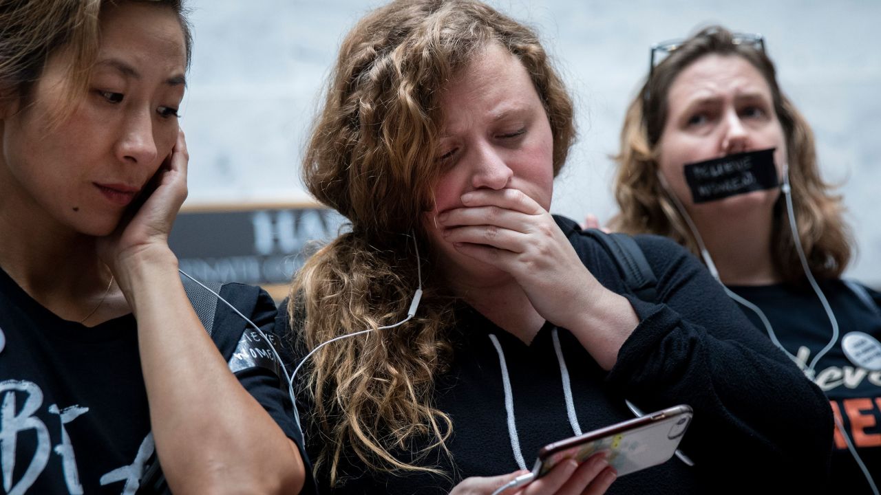 Opponents of the nomination of Judge Brett Kavanaugh watch testimony from Christine Blasey Ford on a smartphone inside an office buidling on Capitol Hill on Thursday.
