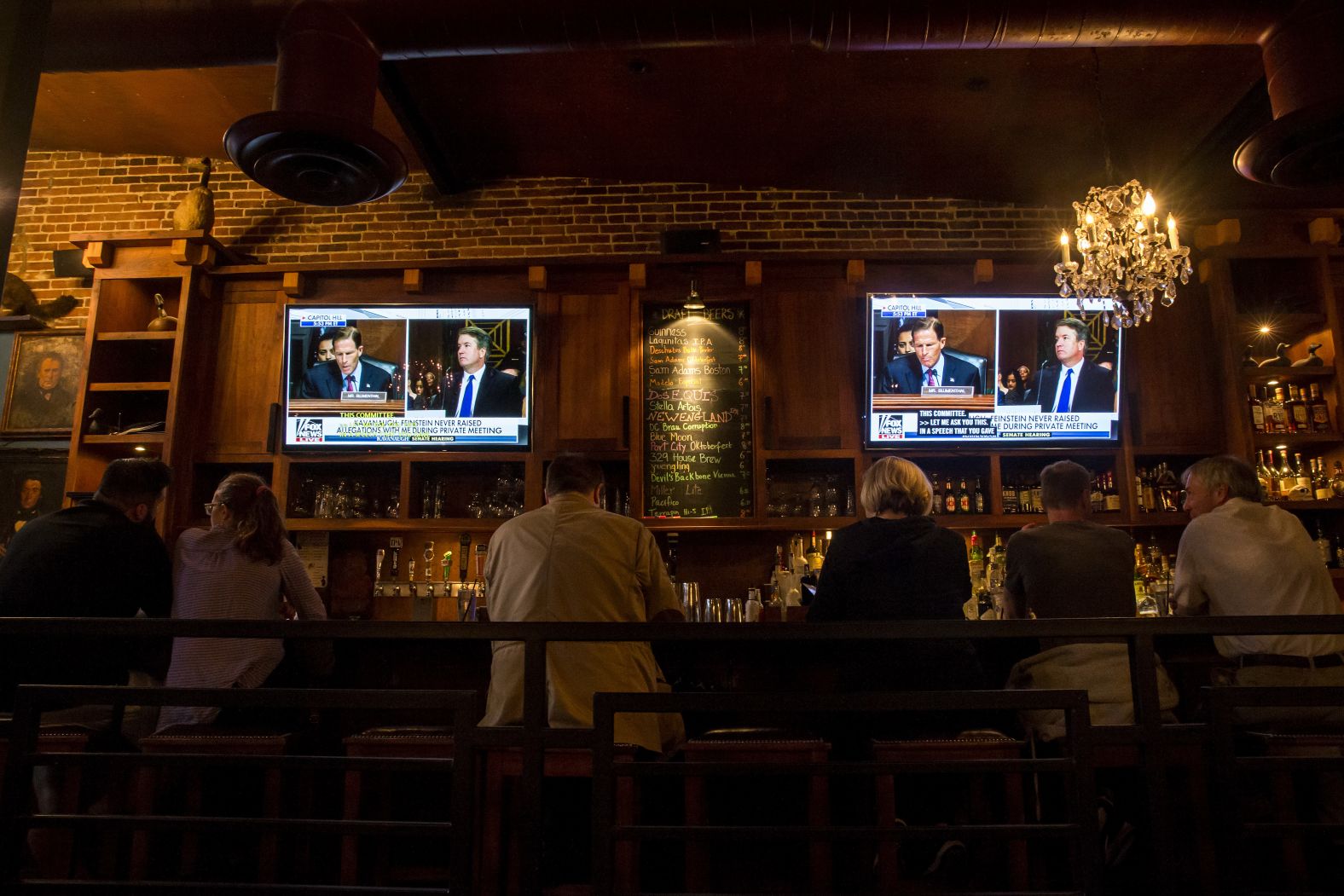 People watch the hearing at a bar in Washington.