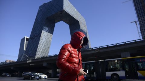 A man walks down the street as the iconic CCTV headquarters loom in the background in the central business district of Beijing on January 20, 2017.