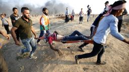 Demonstrators carry an injured Palestinian during clashes along the Israeli border fence, east of Gaza City on September 28, 2018. - Four Palestinians, including a 14-year-old, were killed by Israeli fire in new clashes along the Gaza border today, the health ministry in the Hamas-controlled strip said.