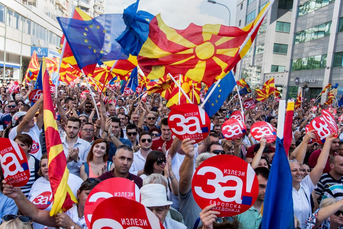 People wave Macedonian and European flags as they attend a rally for the "yes" campaign.