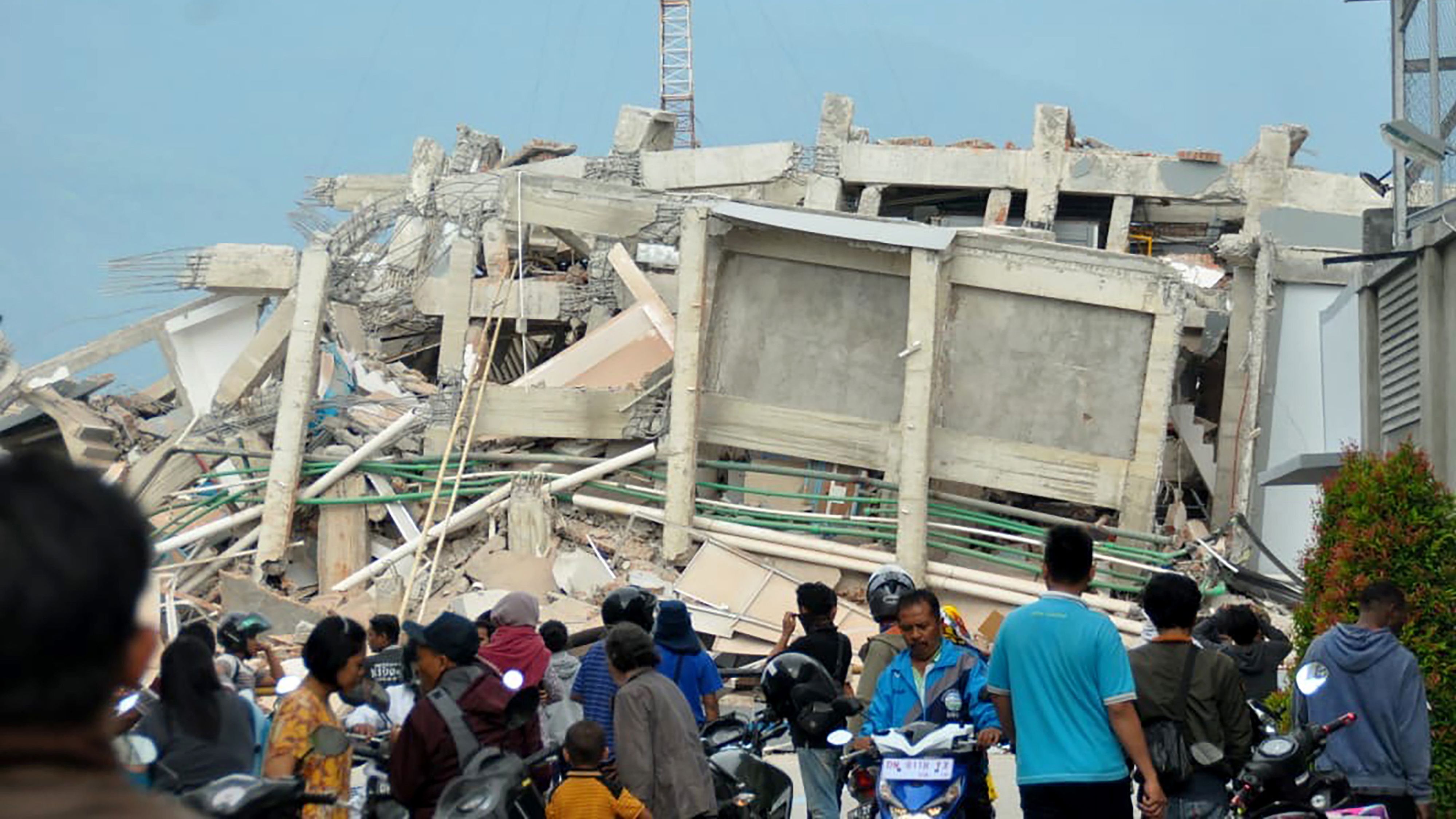 Palu residents gather to look at a collapsed building in the aftermath of the quake and tsunami.