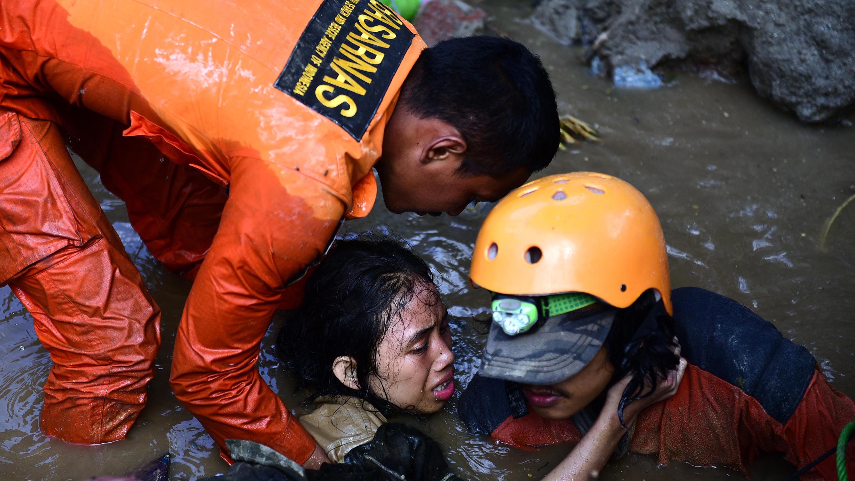 Rescuers try to free a 15-year-old earthquake survivor who was trapped in the flooded ruins of a collapsed house in Palu on Sunday, September 30.