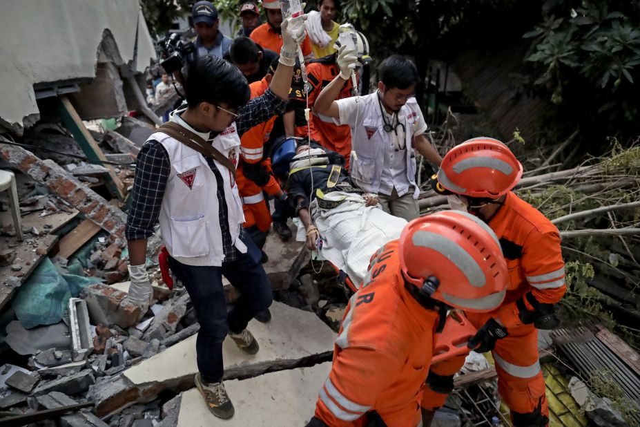 Rescuers move a survivor from a collapsed restaurant building in Palu.
