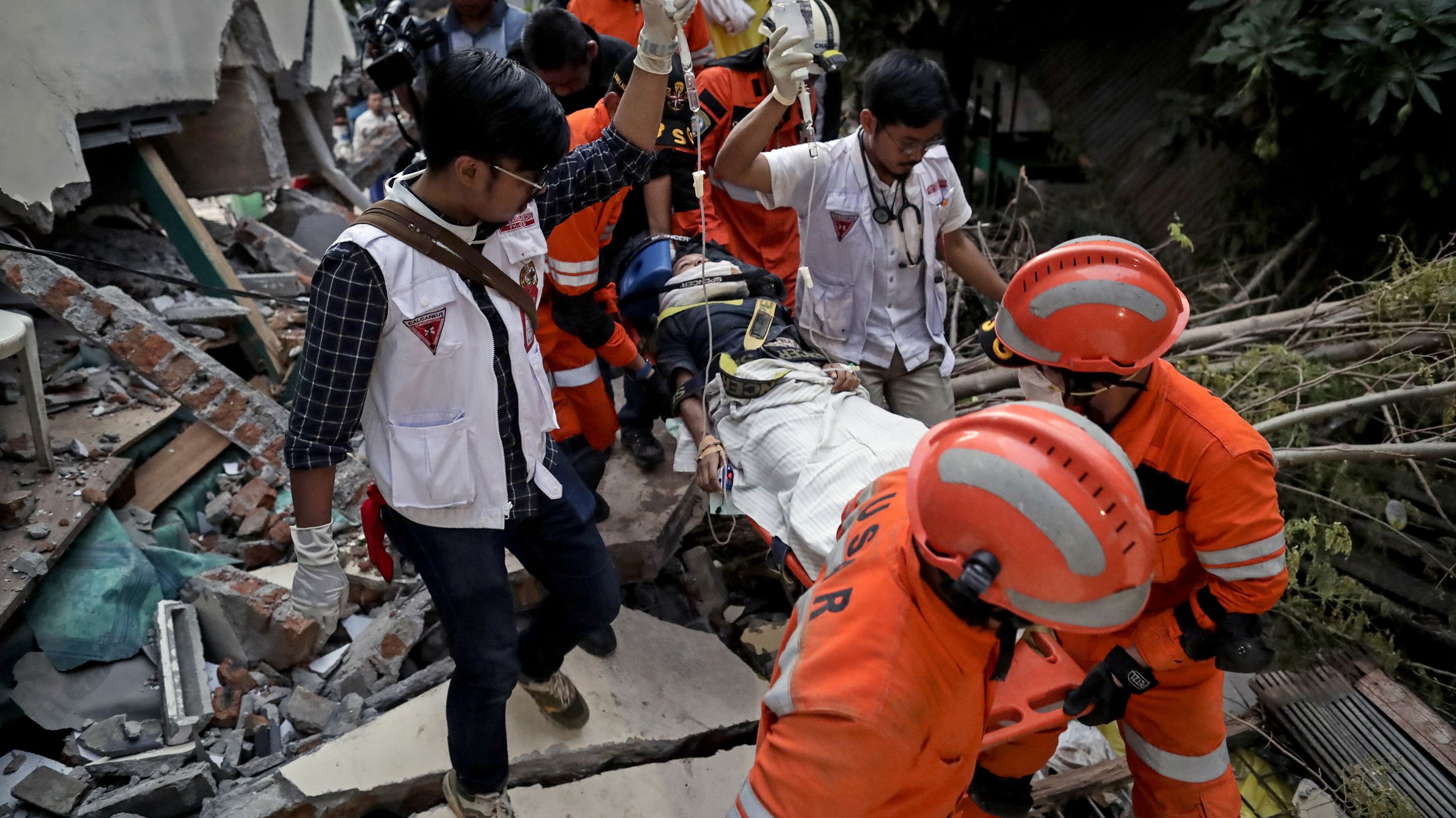 Rescuers move a survivor from a collapsed restaurant building in Palu.