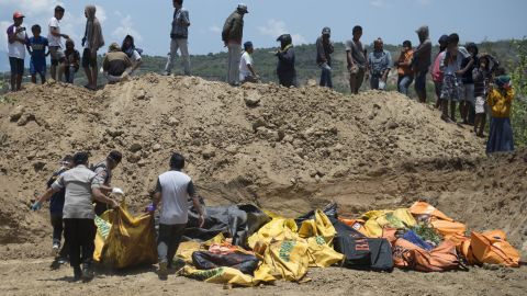 Officials carry body bags into a mass grave ahead of a funeral for quake victims in Palu on Monday.