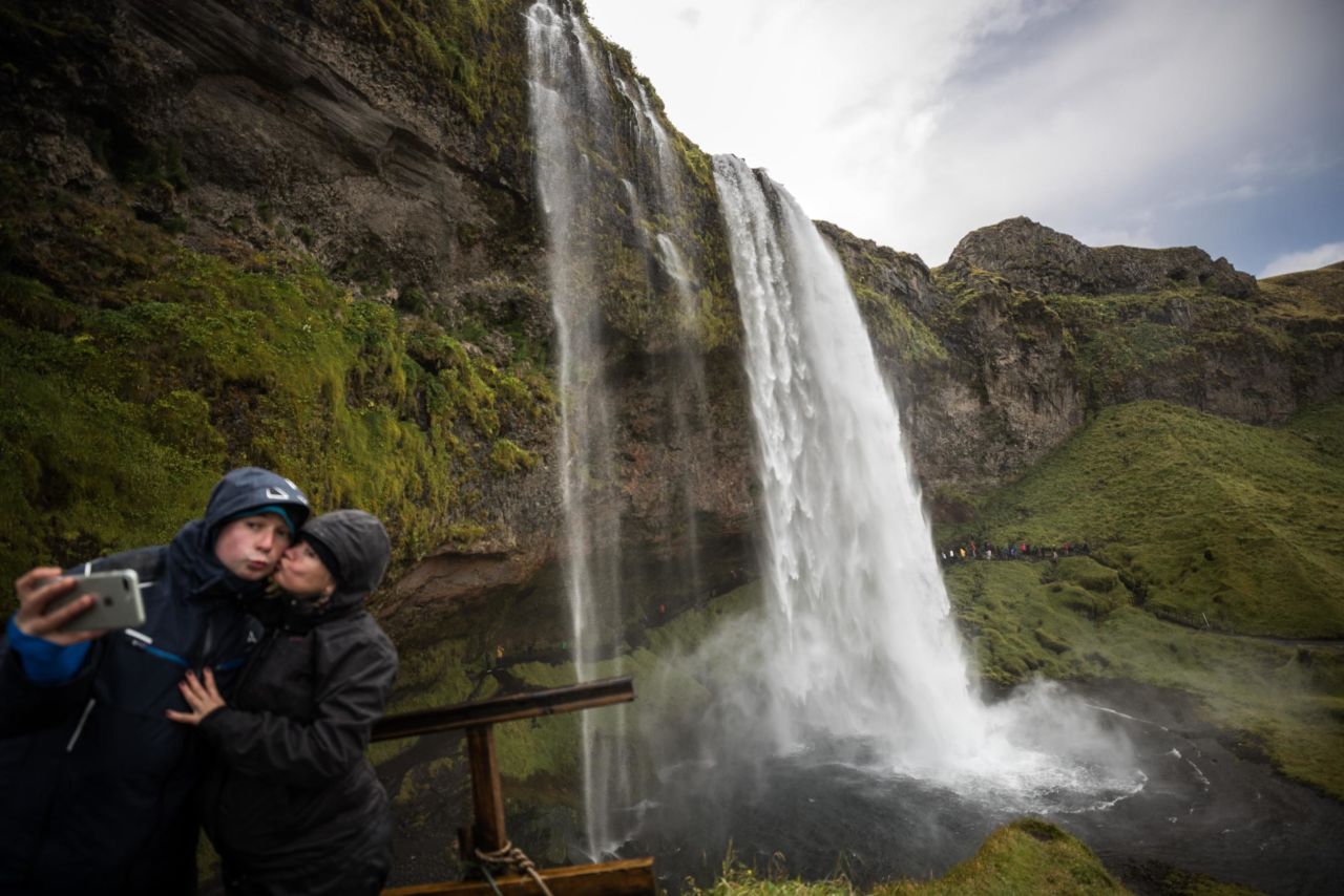The growth of social media is intertwined with Iceland's tourism boom. Pictured here: Tourists take a selfie around Seljalandsfoss waterfall.